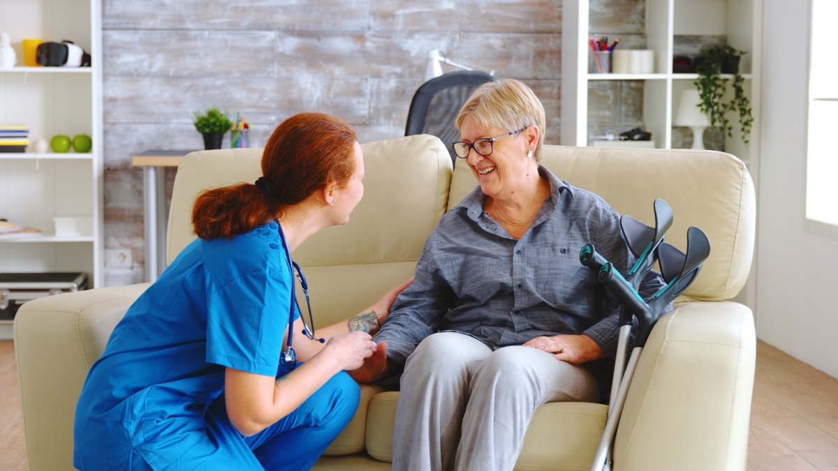 Caring nurse talking with elderly woman in her home