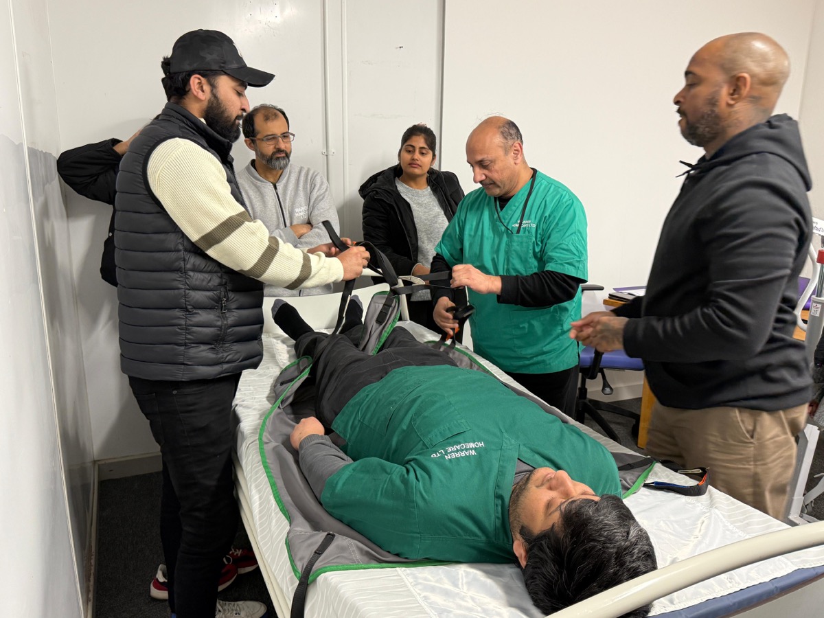 Warren Homecare team learning slide sheet transfer techniques during the train-the-trainer programme