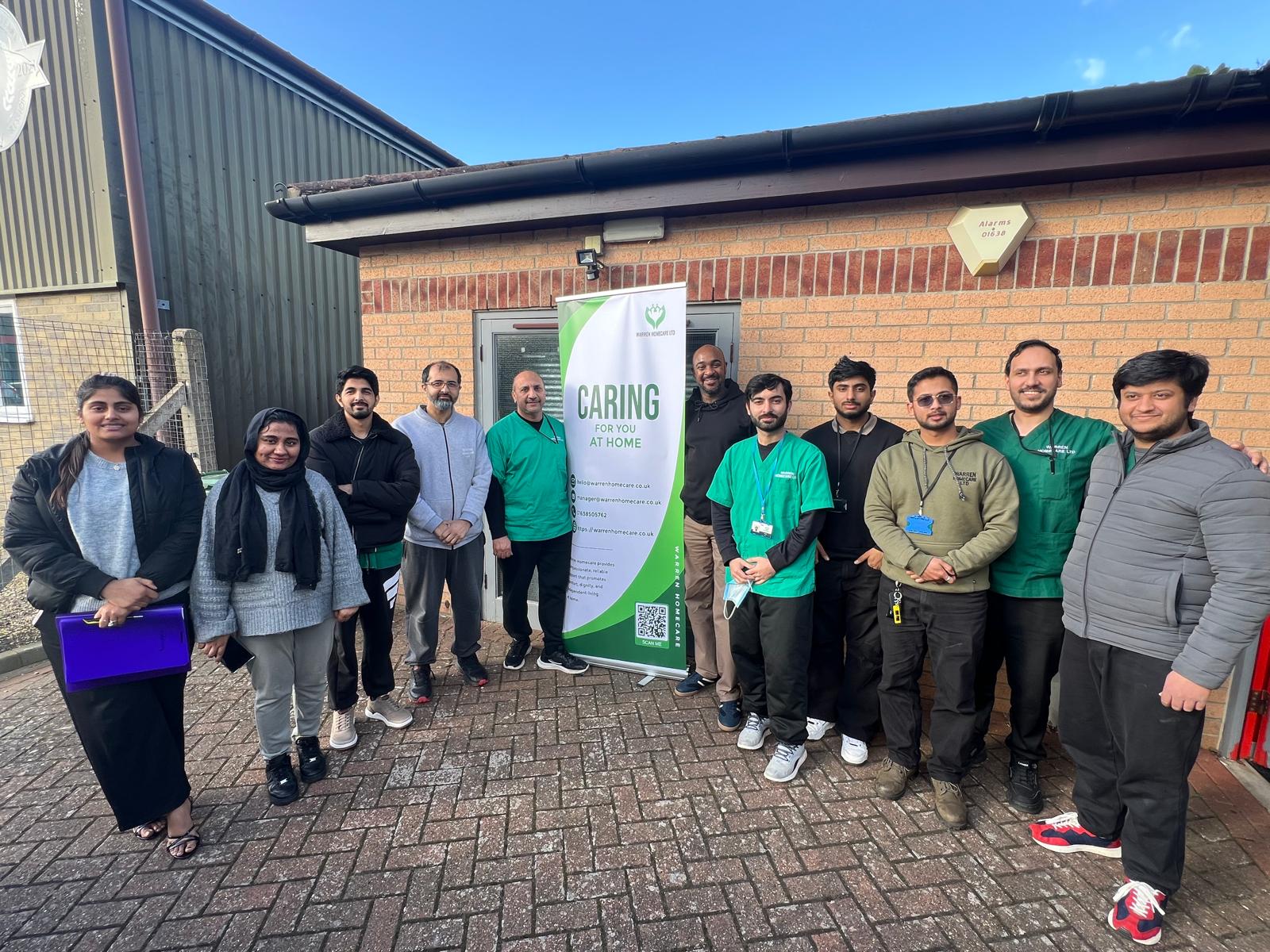 Warren Homecare team gathered around the CARING banner after completing the train-the-trainer programme in March 2026